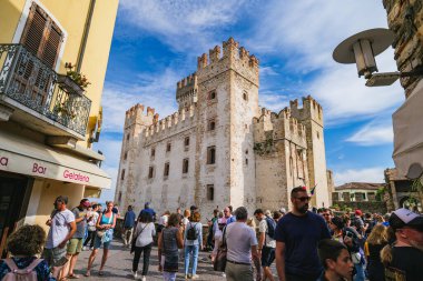 Sirmione, İtalya. Scaligero Kalesi Via Vittorio Emanuele 'den görüldü. Antik ortaçağ köyünün tarihi merkezinde bir grup turist. Turizm ve seyahat kavramı. 2024-09-22.