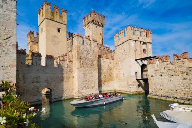 Sirmione, İtalya. Sirmione 'de Castello Scaligero olarak da bilinen Rocca Scaligera manzarası. Bir tekne turistleri şatoda bir tura çıkarıyor. 2025-09-22.