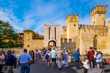 Sirmione, İtalya. Sirmione 'li Castello Scaligero olarak da bilinen Rocca Scaligera manzarası. Turist kalabalığı kale hendeğinin üzerindeki antik asma köprünün girişinden geçiyor. 2025-09-22.