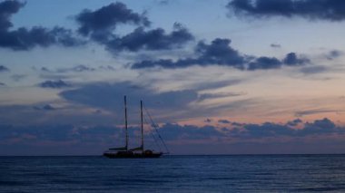 Oglaistro Marina, İtalya. İtalya, Baia Arena, Ogliastro Marina Körfezi 'nde mavi saat deniz manzarası: günbatımından sonra sakin Tyrhenian suları ve yumuşak pastel bulutlar, ufukta iki direkli yelkenli bir gemi. 4K.