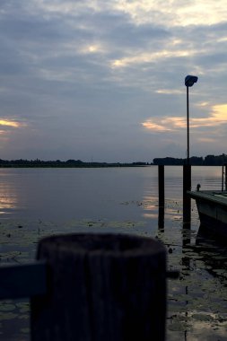 Gün batımında bir gölde lambayla iskele.