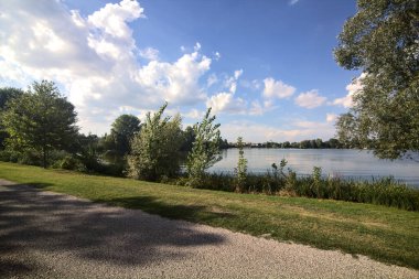 Gün batımında göl kıyısındaki bir parkta toprak yol.