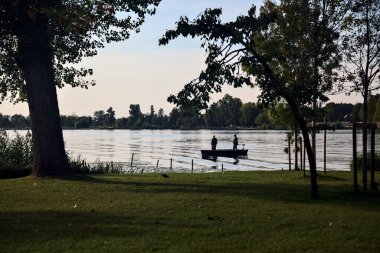 Gün batımında göl kıyısında bir teknede balıkçılar.