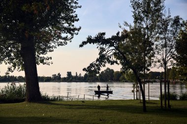 Gün batımında göl kıyısında bir teknede balıkçılar.