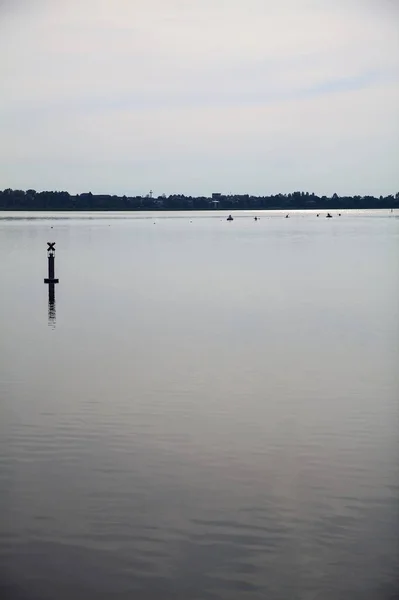 stock image Lake with a pole in the distance on a cloudy day