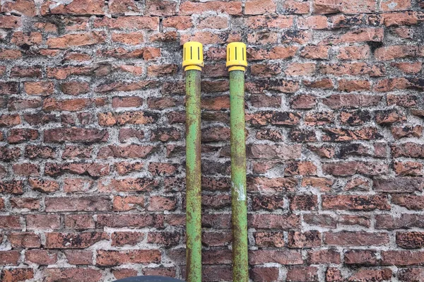 Green pipes on a brick wall