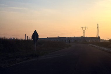 Gün batımında terk edilmiş depoları ve sütunları olan boş bir yol