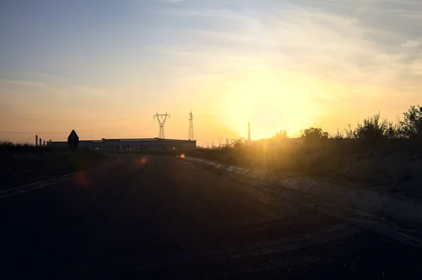 stock image Empty road with abandoned warehouses and pylons at sunset