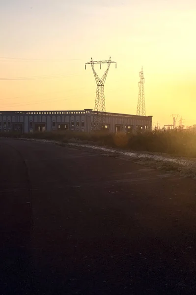 日落时有废弃仓库和挂车的空旷道路 — 图库照片