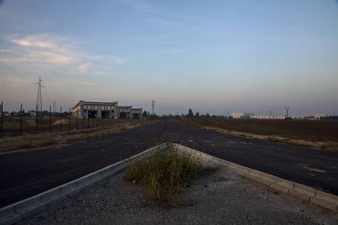 Gün batımında endüstriyel bir tesiste boş bir yolda çatal.