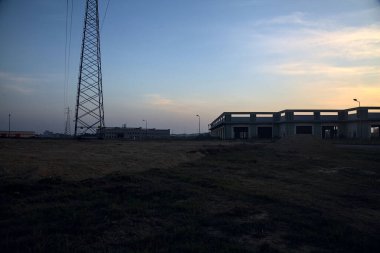 Terk edilmiş depo ve sütunlar gün batımında bir sanayi tesisinde kavşağın yanında.