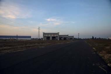 Gün batımında terk edilmiş depoları ve sütunları olan boş bir yol