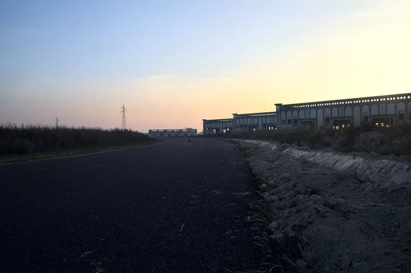 stock image Empty road with abandoned warehouses and pylons at sunset