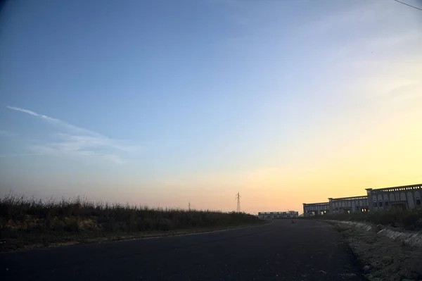 Stock image Empty road with abandoned warehouses and pylons at sunset