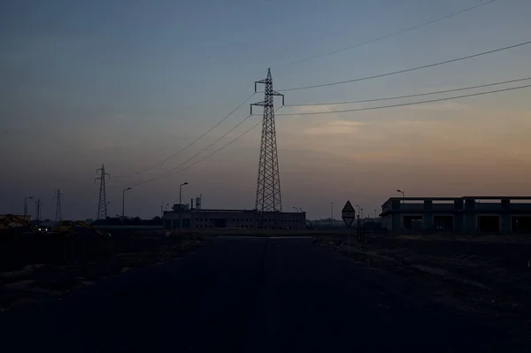 Abandoned warehouses and pylons next to a roundabout in an industrial complex at sunset