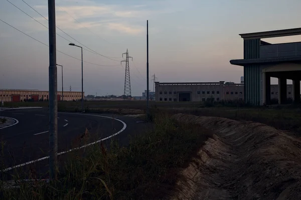 日落时分 在一个工业园区的转盘旁 废弃的仓库和挂塔 — 图库照片