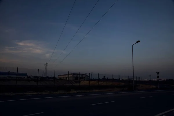 Leere Straße Mit Verlassenen Lagerhallen Und Strommasten Bei Sonnenuntergang — Stockfoto