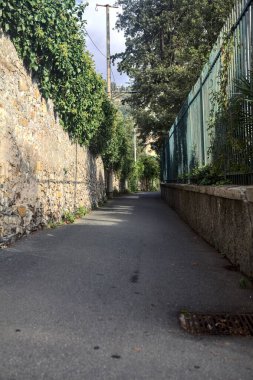 Dar sokaklar taş bir duvarla çevrili ve her iki tarafında bitkiler olan çitlerle çevrili.