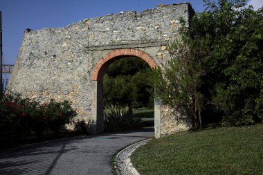 Yol parktaki eski bir sınır duvarının kemerinden geçiyor.