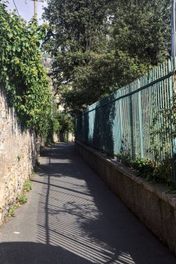 Dar sokaklar taş bir duvarla çevrili ve her iki tarafında bitkiler olan çitlerle çevrili.