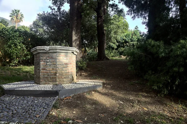 stock image Old brick well next to a bush in a park