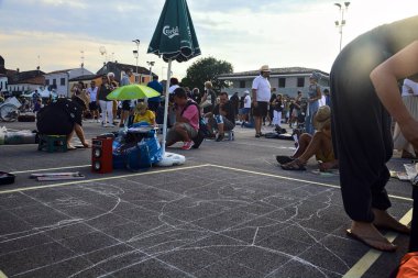 Gün batımında asfalta kutsal resimler çizerken bir kongredeki sokak ressamları