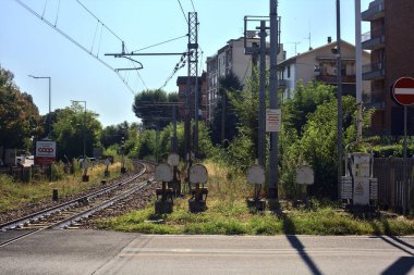 Gün batımında yanında ağaçlar ve binalar olan demiryolu geçidi