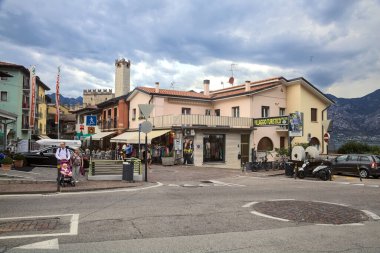 Malcesine 'in girişindeki kavşakta bulutlu bir günde insanlar geçiyor ve alışveriş yapıyorlar.