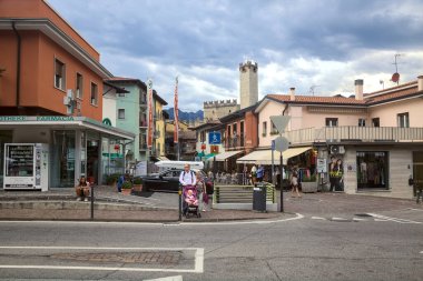 Malcesine 'in girişindeki kavşakta bulutlu bir günde insanlar geçiyor ve alışveriş yapıyorlar.