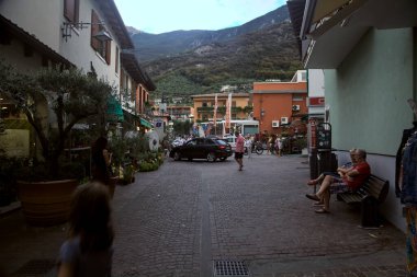 Dükkanları olan dar bir sokak ve küçük bir kasabadan geçen insanlar.