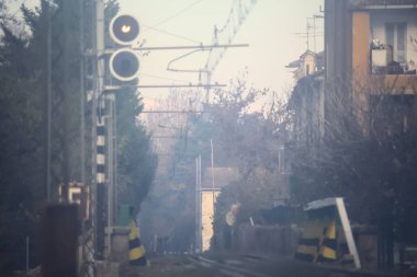Sonbaharda sisli bir günde, kenarında işaretler ve çıplak ağaçlar olan tren yolu.