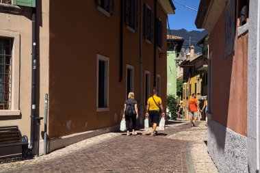 Dükkanları olan dar bir sokak ve küçük bir kasabadan geçen insanlar.