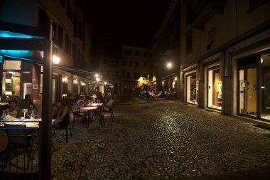 Restoranı olan bir meydan ve geceleri yemek yiyen insanlar.