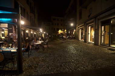 Restoranı olan bir meydan ve geceleri yemek yiyen insanlar.