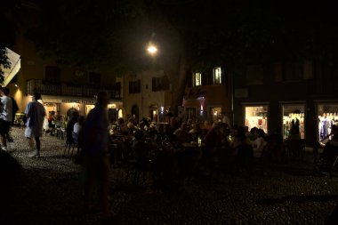 Restoranı olan bir meydan ve geceleri yemek yiyen insanlar.