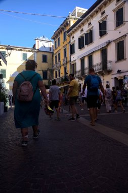 Dükkanlarla dolu dar bir cadde ve eski bir köyden geçen insanlar.