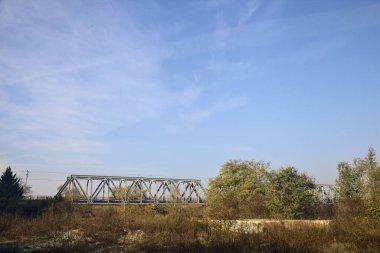 Kırsal kesimde arka planda köprüsü olan çamurlu bir yol.