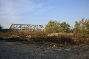 Kırsal kesimde arka planda köprüsü olan çamurlu bir yol.