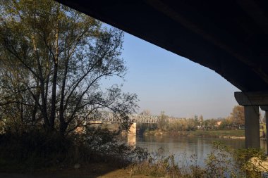 Sonbaharın açık bir gününde köprünün çerçevelediği uzaklıktaki demiryolu köprüsü