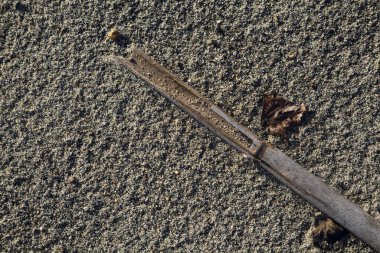 Kumun üzerinde kırık bir baston. Yakından görülüyor.