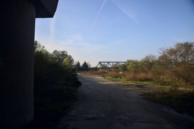 Kırsal kesimde arka planda köprüsü olan çamurlu bir yol.