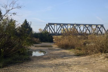 Kırsal kesimde arka planda köprüsü olan çamurlu bir yol.