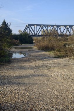 Kırsal kesimde arka planda köprüsü olan çamurlu bir yol.