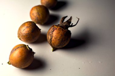 Gri bir yüzeyde gül kalçalar. Yakından görülüyor.