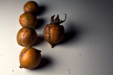 Gri bir yüzeyde gül kalçalar. Yakından görülüyor.