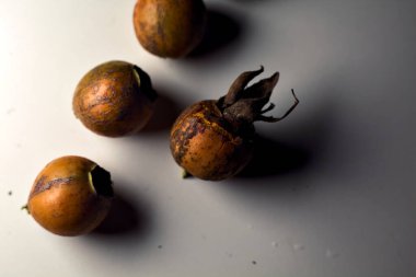 Gri bir yüzeyde gül kalçalar. Yakından görülüyor.