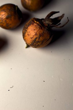 Gri bir yüzeyde gül kalçalar. Yakından görülüyor.