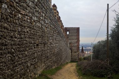 Bulutlu bir günde, uzak bir yerde çan kulesi olan parktaki antik bir kalenin yanındaki toprak yol.
