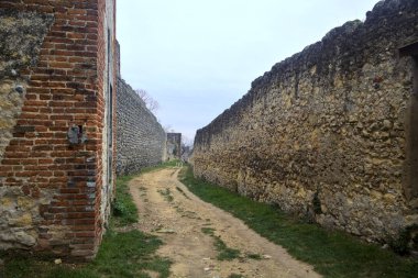 Bulutlu bir günde parkta tahkimatla çevrelenmiş toprak yol.