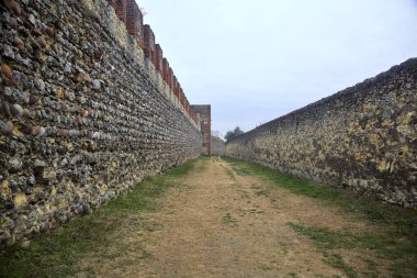 Bulutlu bir günde parkta tahkimatla çevrelenmiş toprak yol.